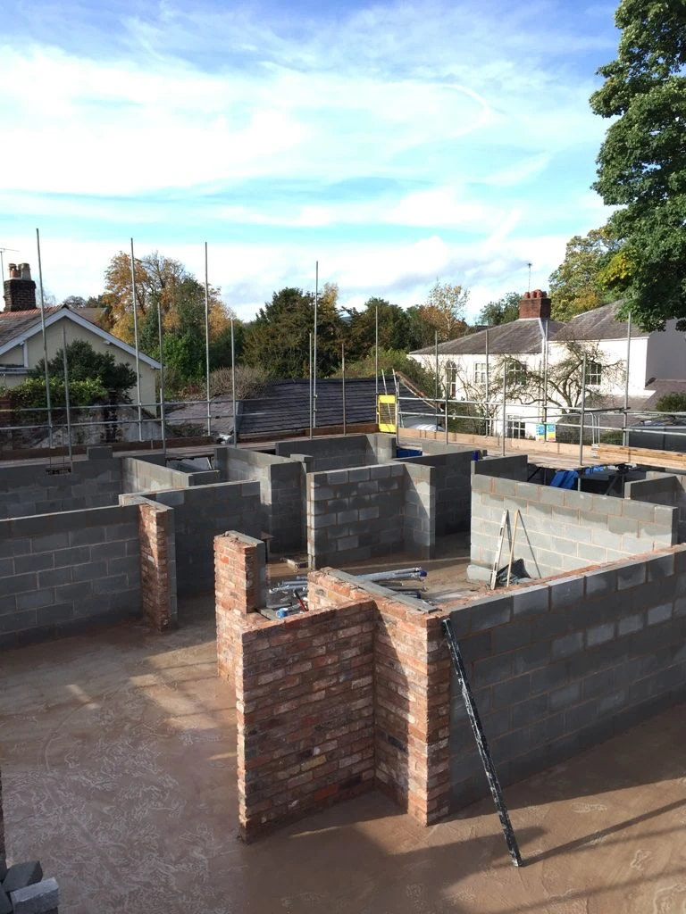 A house under construction with a brick wall.